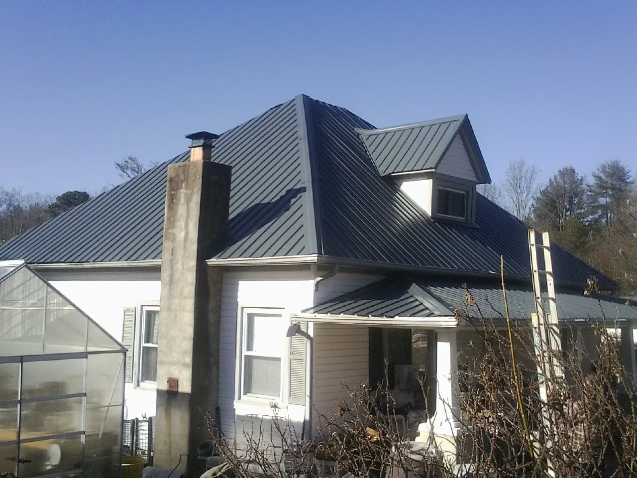 Dark blue standing seam metal roof on a white farmhouse with dormer — Slate & Tile Roof Repair by Roofing Brothers in Cardiff By The Sea