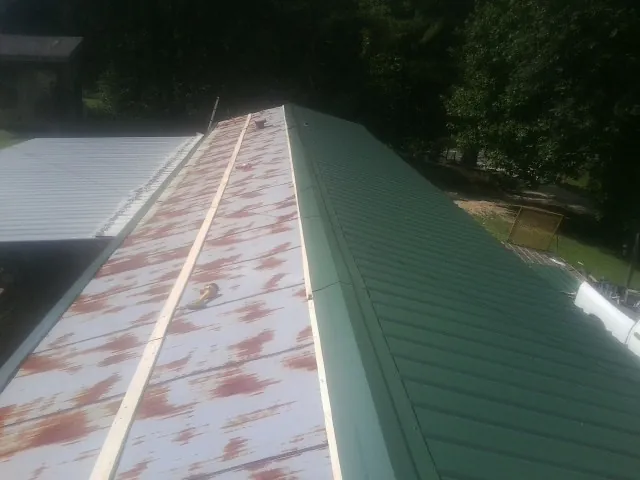 Old rusted panels beside newly installed green metal roofing — Wind Damage Roof Repair by Roofing Brothers in Cardiff By The Sea