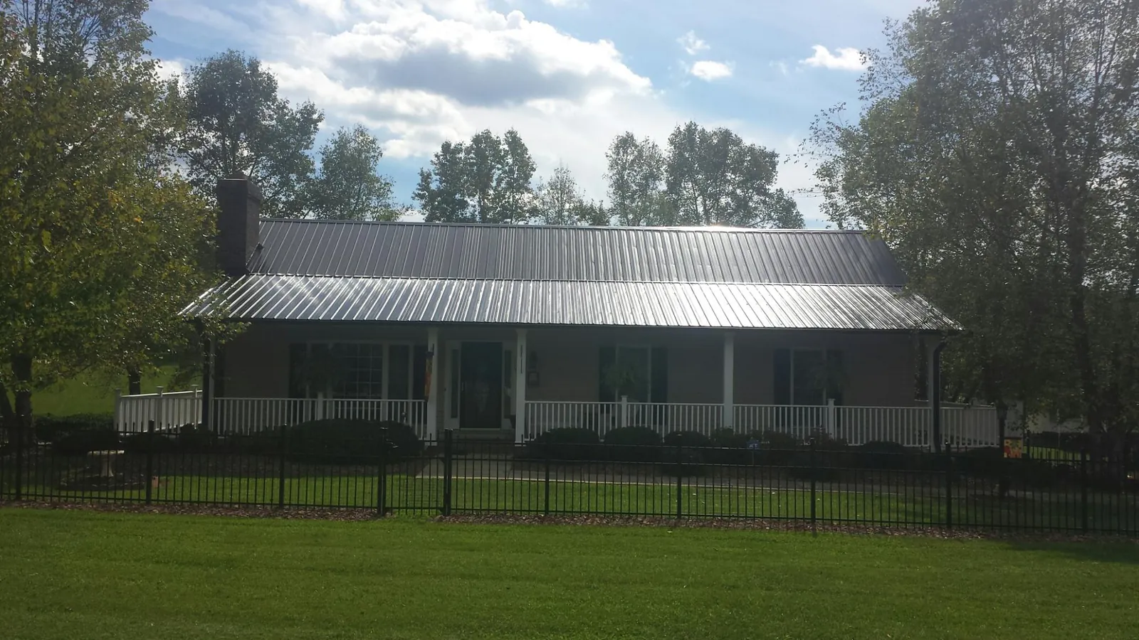 Gray metal roof on a brick ranch with a full width front porch — Gutter Guard Installation work by our crew in Cardiff By The Sea