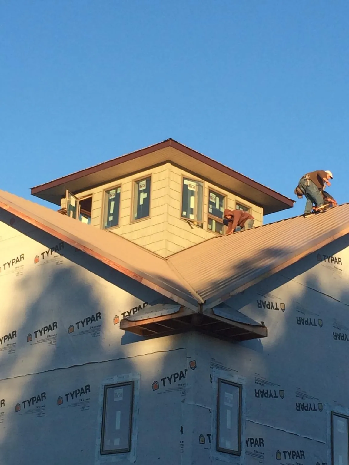 Roofers working around a rooftop cupola on a new metal roof at sunset — Roof Waterproofing in Cardiff By The Sea by Roofing Brothers
